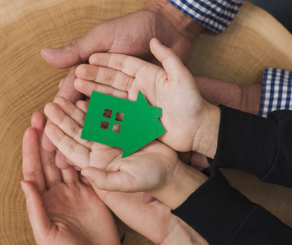 Manos sujetando una figura de una casa, representando la confianza